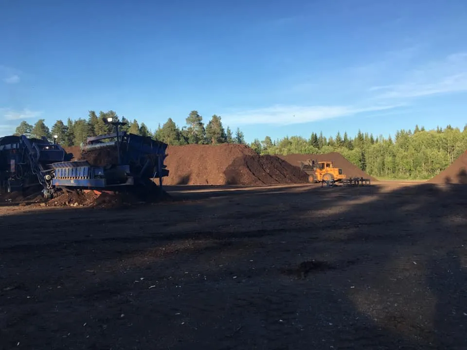 Industriplanen med blått sorteringsverk, hjullastare och barkhögar