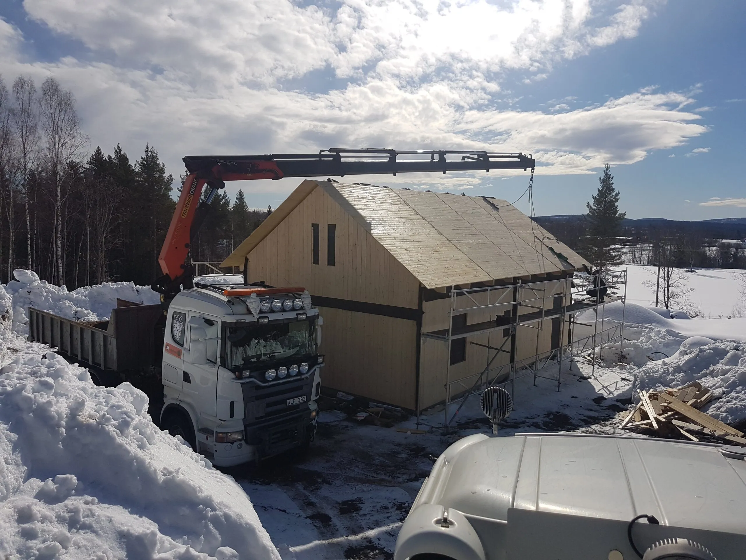 Kranbil vid ett hus under byggnation i snö