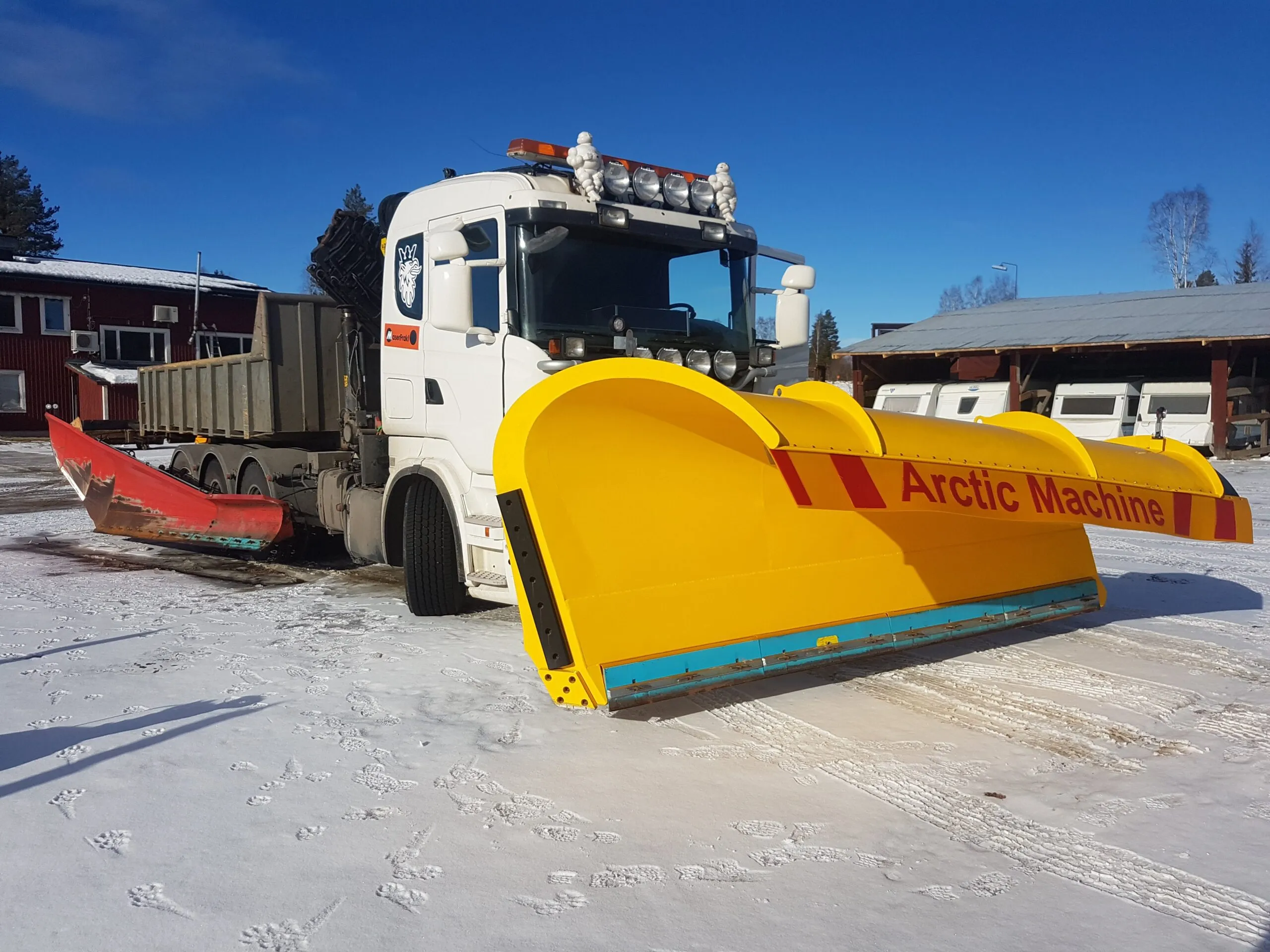Vit lastbil med gul Arctic Machine-plog